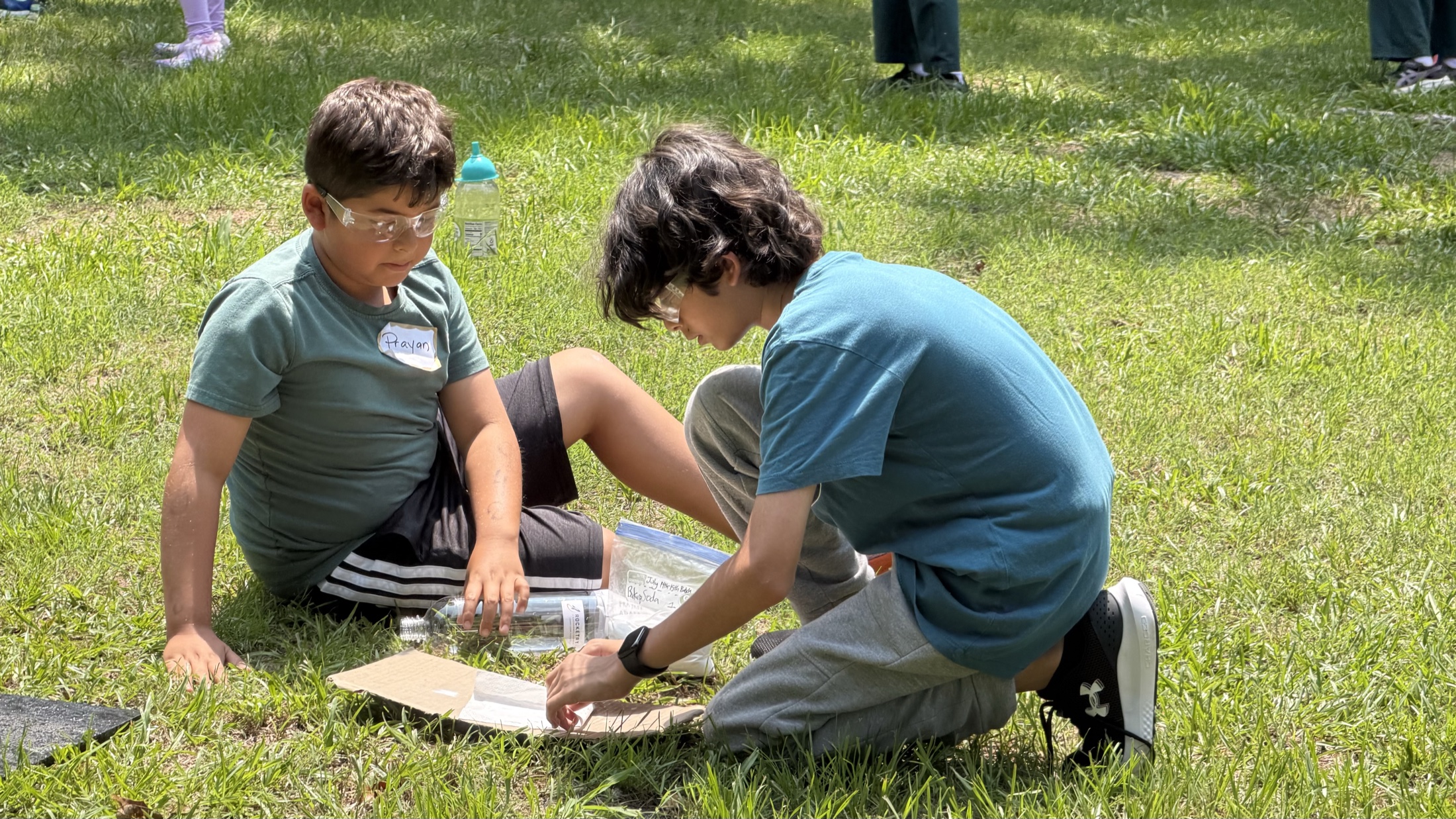 Two students working together on a rocket project outdoors